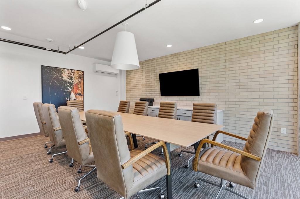 a conference room with a table and chairs and a tv on the wall at The Revival, Utah