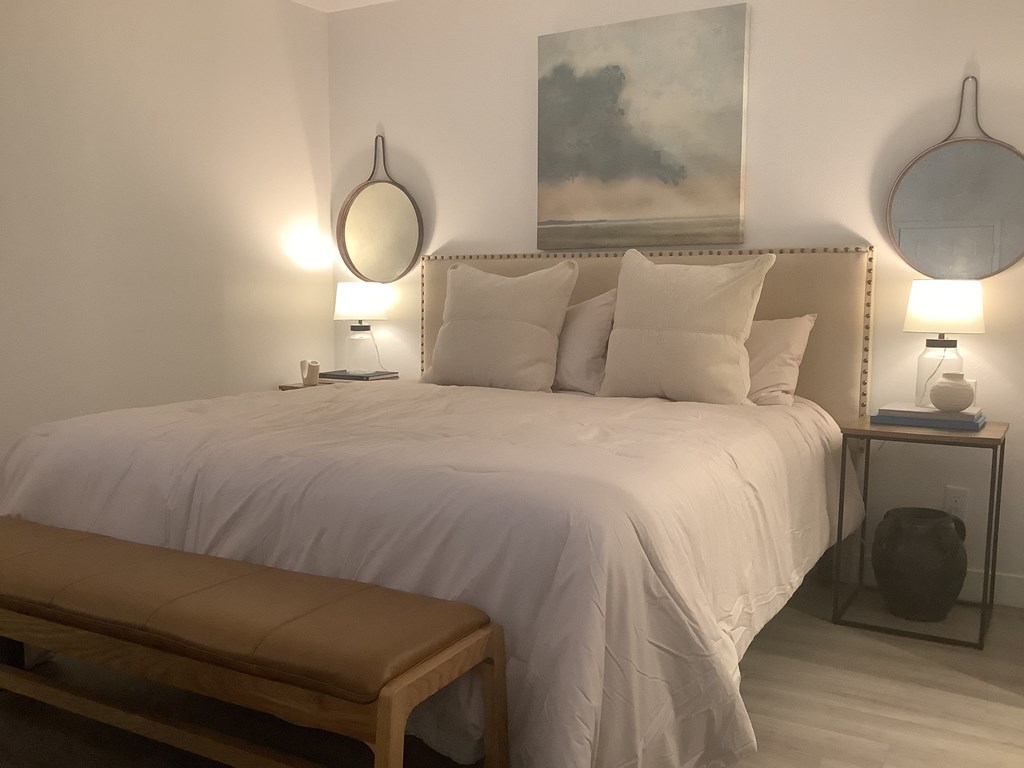 a white bedroom with a bed and two mirrors