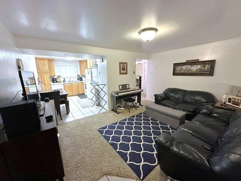 A living room with a black leather couch and a rug.