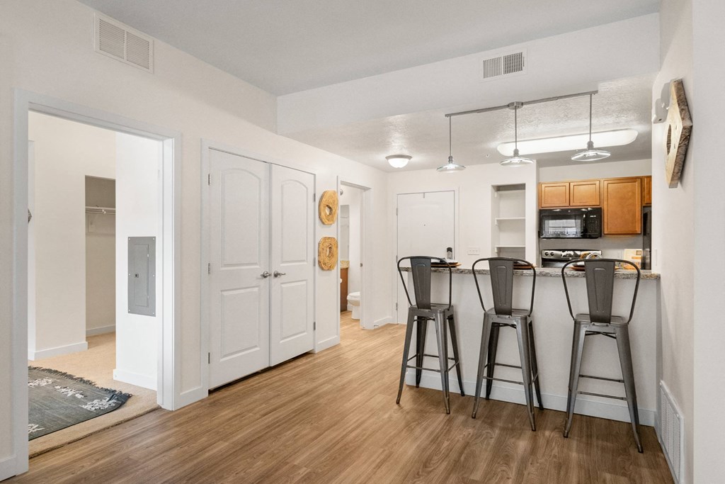 a living room with bar stools and a kitchen with stools