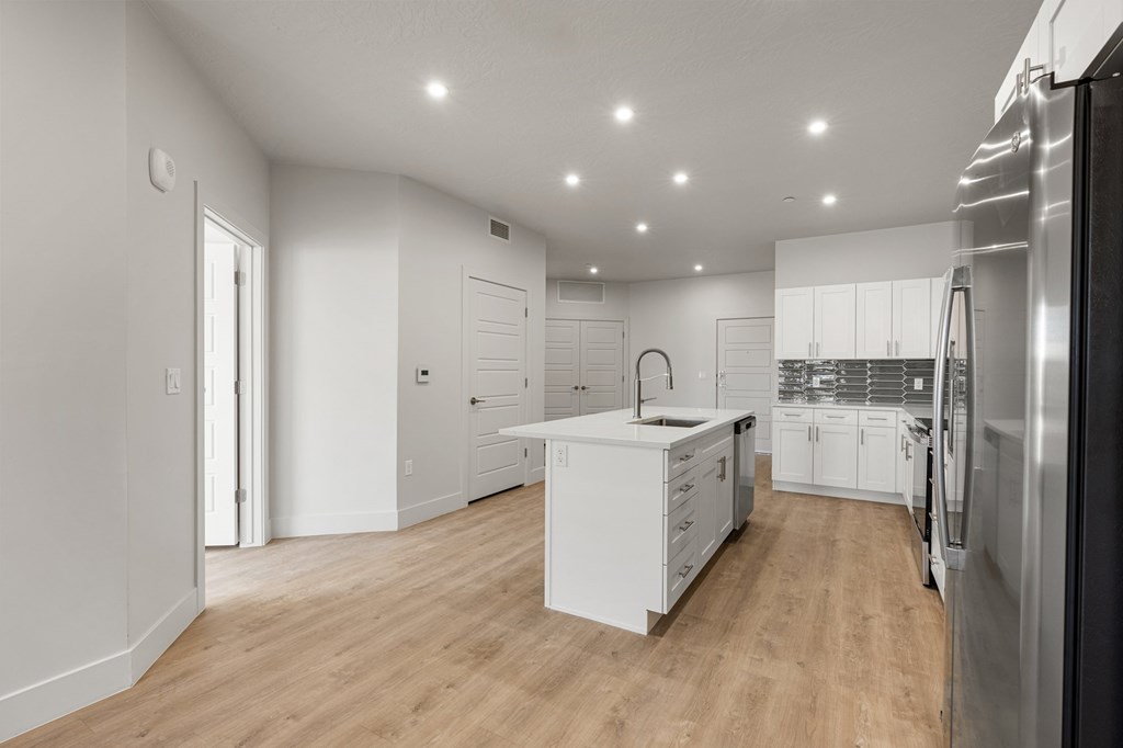 A modern kitchen with white cabinets and a wooden floor. at The Vue At Desert Color, St. George, 84790