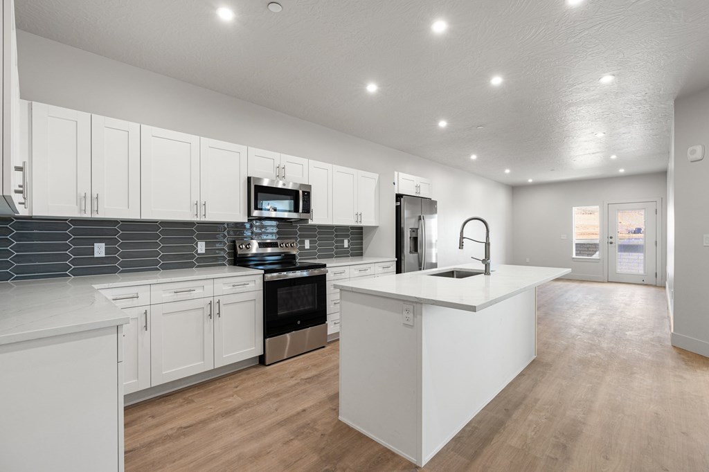 A modern kitchen with white cabinets and a wooden floor. at The Vue At Desert Color, Utah, 84790