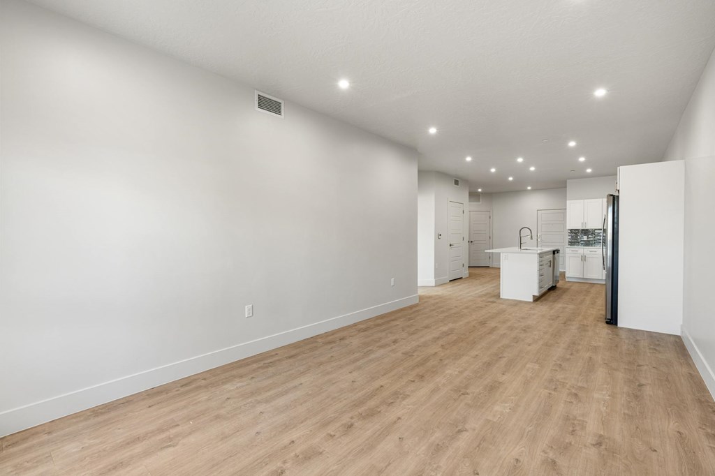 A large empty room with wooden flooring and white walls. at The Vue At Desert Color, St. George, UT