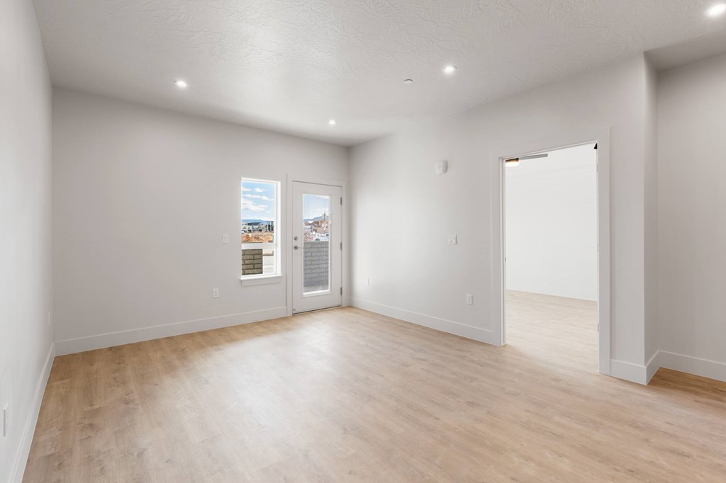 A large empty room with wooden floors and white walls. at The Vue At Desert Color, St. George, UT, 84790