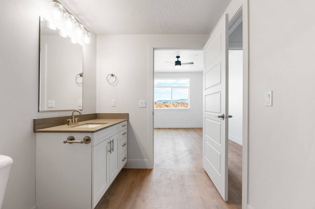 A bathroom with a sink, mirror, and wooden floors. at The Vue At Desert Color, Utah, 84790