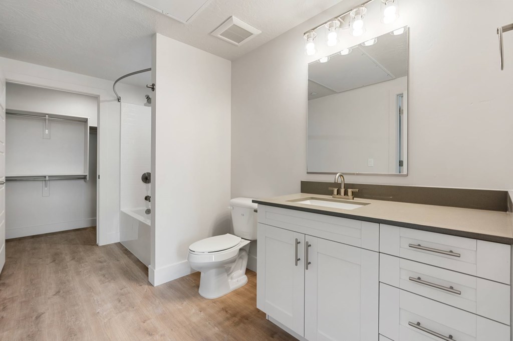 A white toilet sits in a bathroom with a sink and mirror. at The Vue At Desert Color, St. George, UT