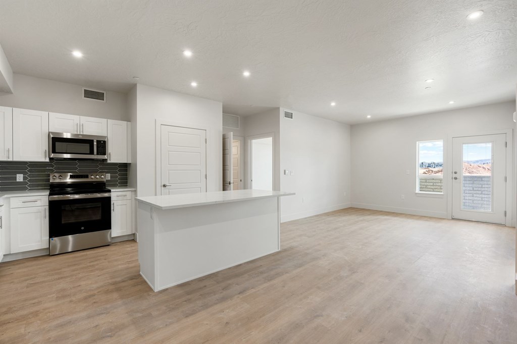 A spacious kitchen with white cabinets and a wooden floor. at The Vue At Desert Color, Utah, 84790