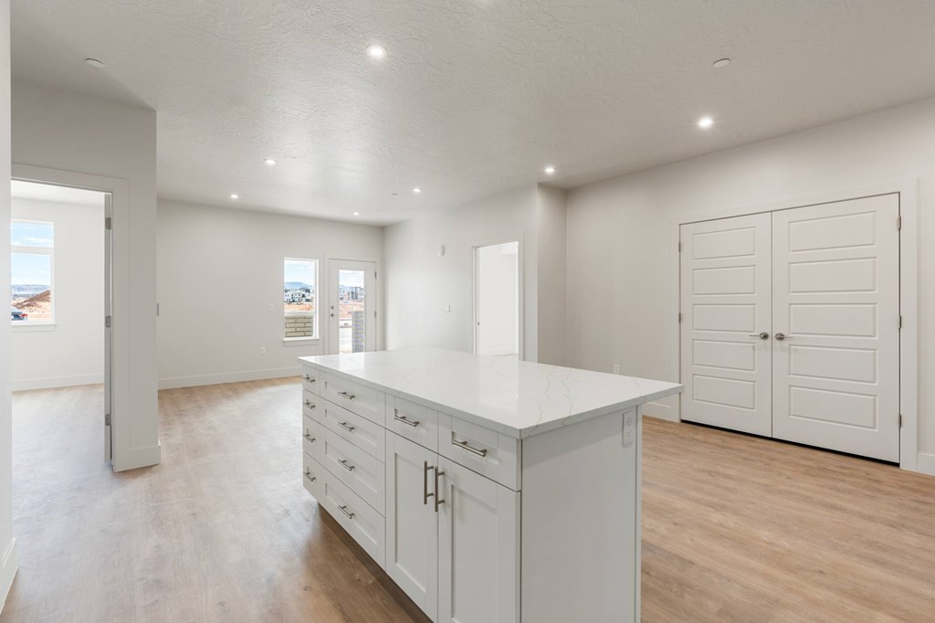A white kitchen with wooden floors and white cabinets. at The Vue At Desert Color, St. George, UT, 84790