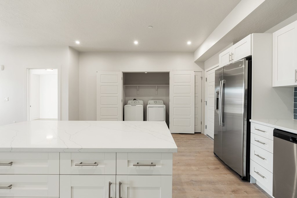 A modern kitchen with white cabinets and a stainless steel refrigerator. at The Vue At Desert Color, St. George, UT, 84790