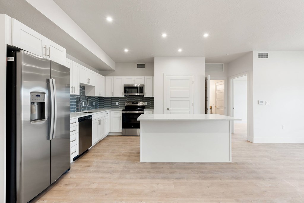 A modern kitchen with a refrigerator on the left and a countertop in the middle. at The Vue At Desert Color, St. George, Utah