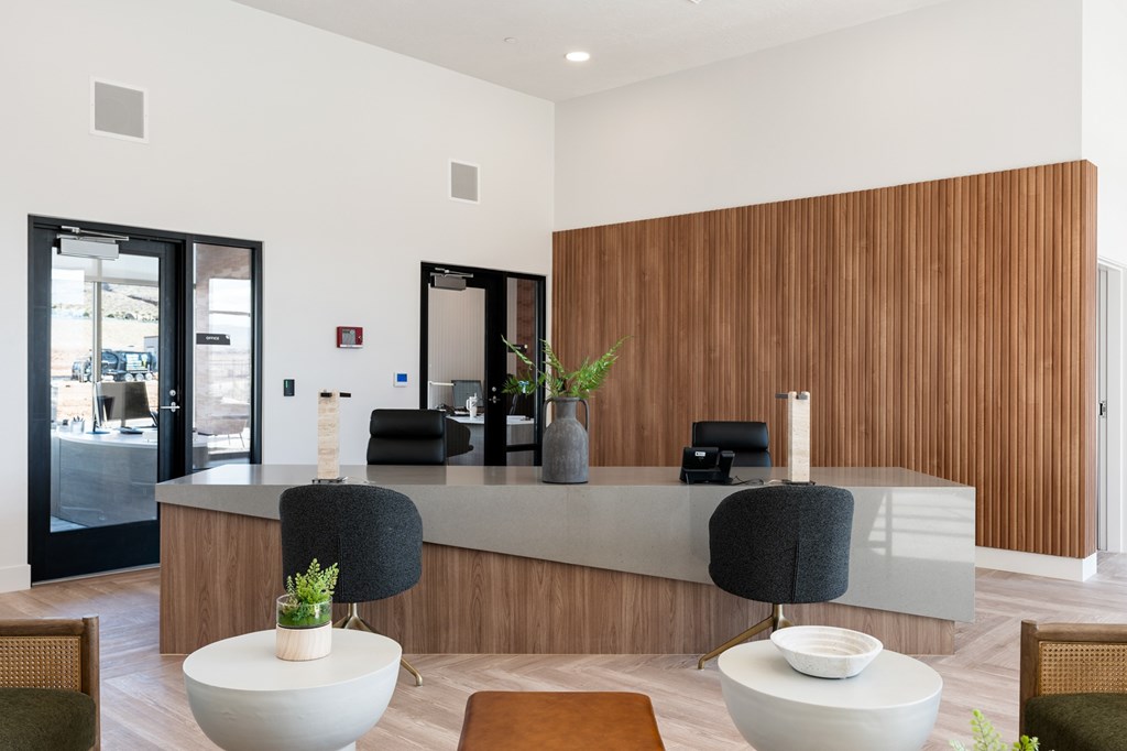A reception area with a white counter and two black chairs. at The Vue At Desert Color, St. George, 84790