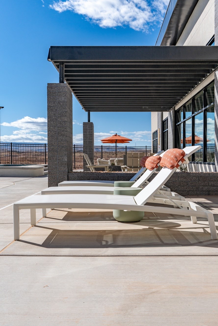 A person is sitting on a white chair under a black awning. at The Vue At Desert Color, St. George, UT