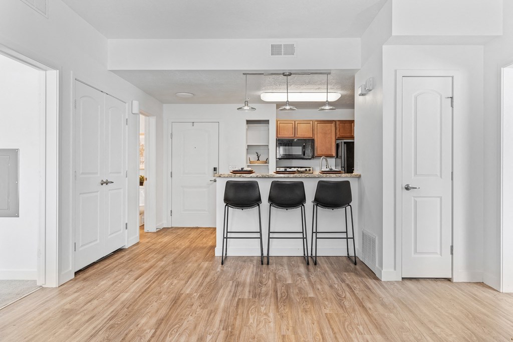 the living room and kitchen of a house with white walls and wood floorsat The View on 20th, Ogden, 84401