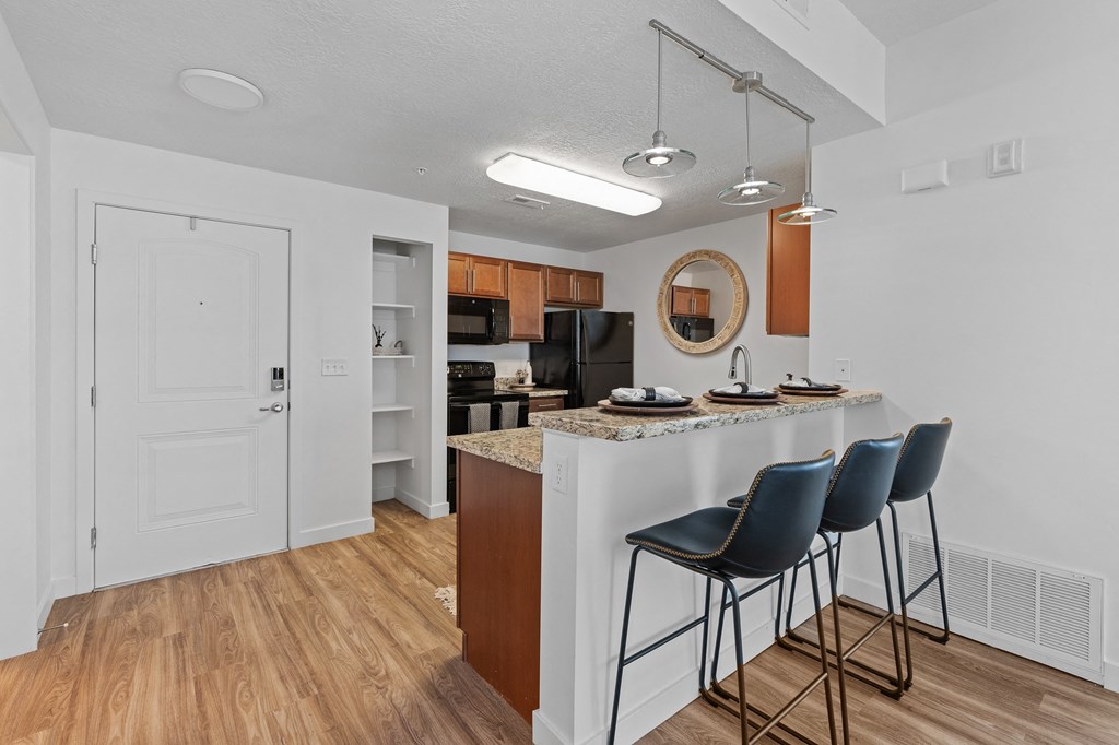 a kitchen with bar stools and a breakfast bar with three stoolsat The View on 20th, Ogden, UT