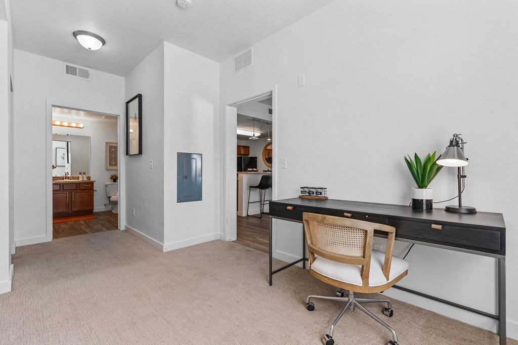 an office space with a desk and a chair and a doorway to a bathroomat The View on 20th, Ogden