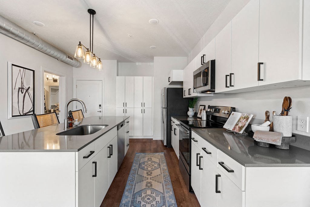 a large kitchen with black counters and white cabinets at The Revival, Salt Lake City, UT