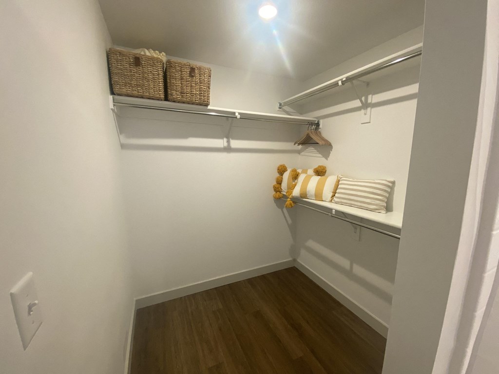 a walk in closet with white walls and a white shelf with baskets on it