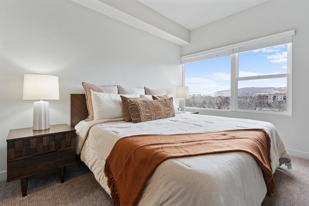 A bedroom with a large bed and a window overlooking a cityscape at Wilmington Flats Apartments, Salt Lake City