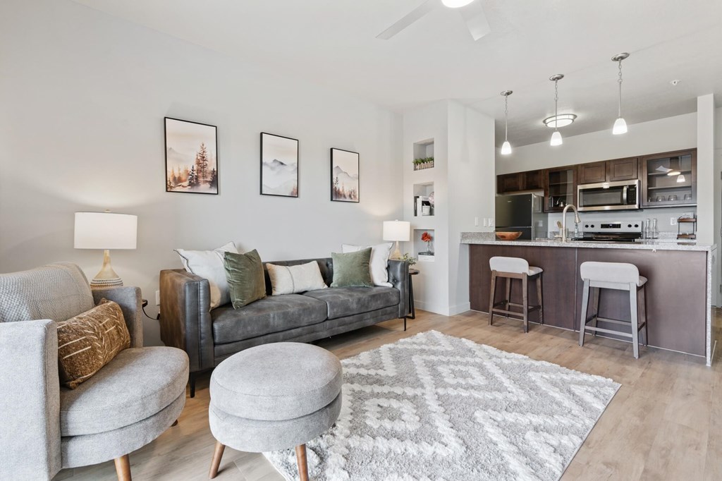 A modern living room with a grey couch, a grey ottoman, and a grey rug at Wilmington Flats Apartments, Salt Lake City, 84106
