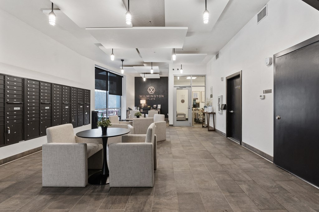 A black and white image of a modern office lobby with a table and chairs at Wilmington Flats Apartments, Utah, 84106