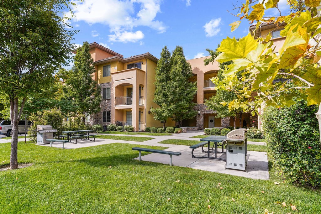 a park with picnic tables and benches in front of a building at Siena Villas Apartments, Orem
