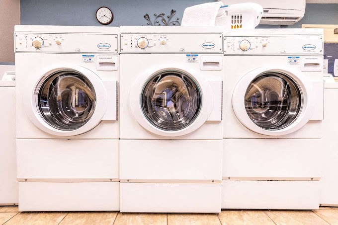 a row of white washing machines in a laundry room