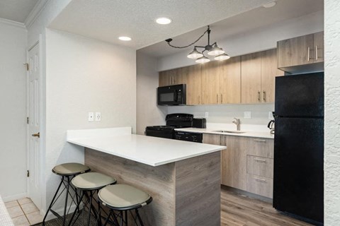 a kitchen with a white counter top and a black refrigerator