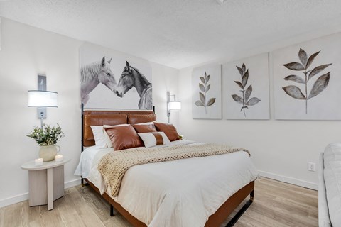 a bedroom with a bed and paintings of horses at AVIA Lofts on Liberty Ridge Apartments, Jacksonville