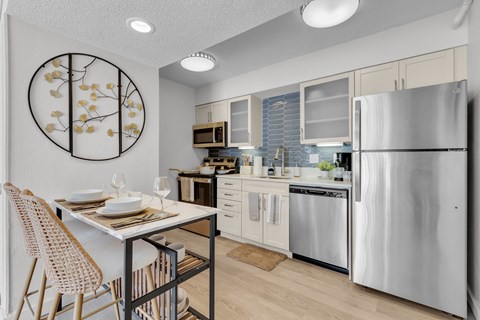 a kitchen with stainless steel appliances and a table with chairs at AVIA Lofts on Liberty Ridge Apartments, Jacksonville, FL
