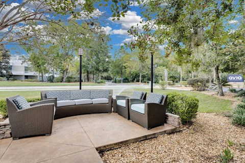 a patio with couches and chairs and trees at AVIA Lofts on Liberty Ridge Apartments, Florida, 32256
