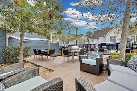 an outdoor patio with tables and chairs and trees at AVIA Lofts on Liberty Ridge, Jacksonville, FL