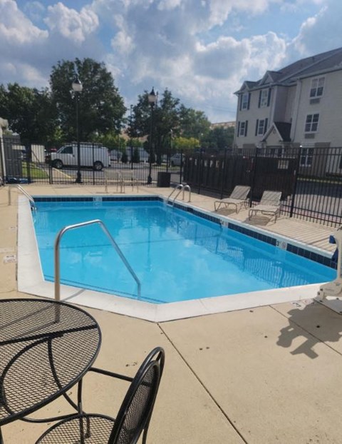 a swimming pool with chairs and a fence around it