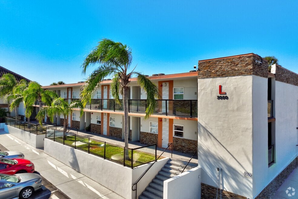 a building with palm trees in front of it and a parking lot