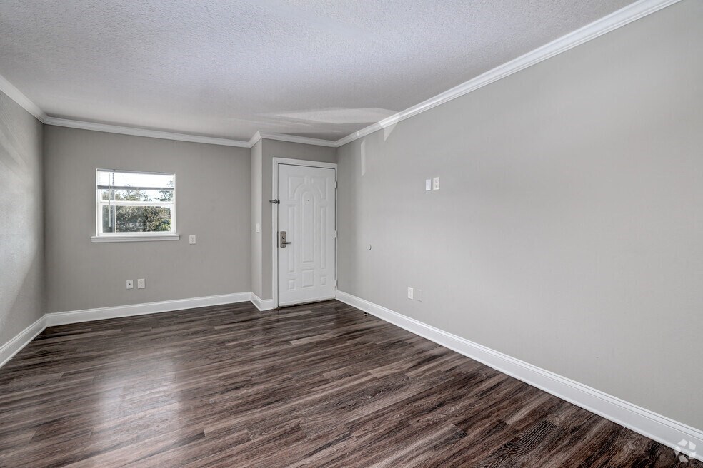 an empty living room with wood flooring and a window
