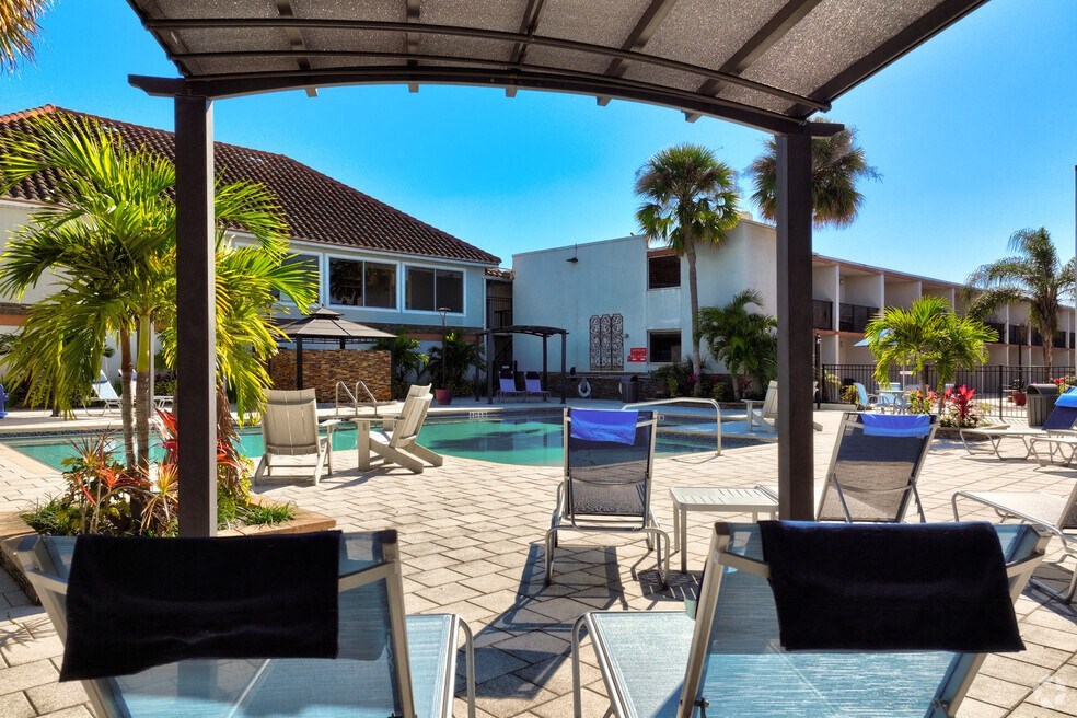 a swimming pool with tables and chairs in front of a house