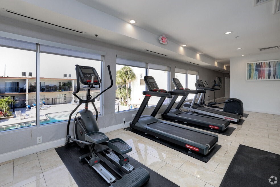 the gym is equipped with cardio equipment and a view of the pool