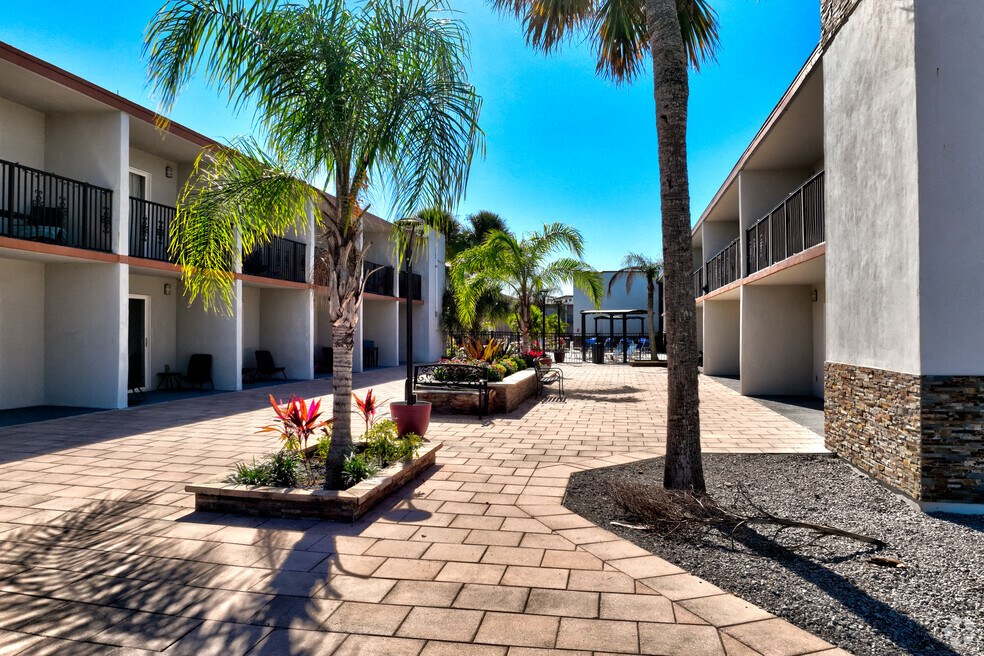a courtyard with palm trees in front of a building