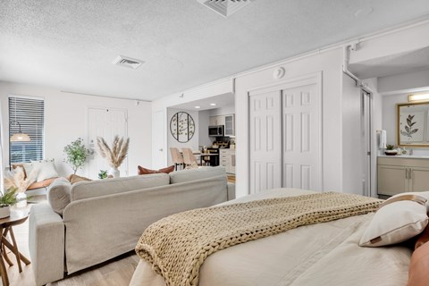 a bedroom with a bed and a living room with a couch at AVIA Lofts on Liberty Ridge Apartments, Jacksonville, Florida