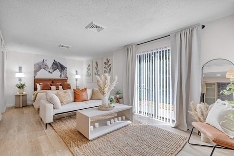 a living room with a couch and a sliding glass door to a bedroom at AVIA Lofts on Liberty Ridge Apartments, Jacksonville