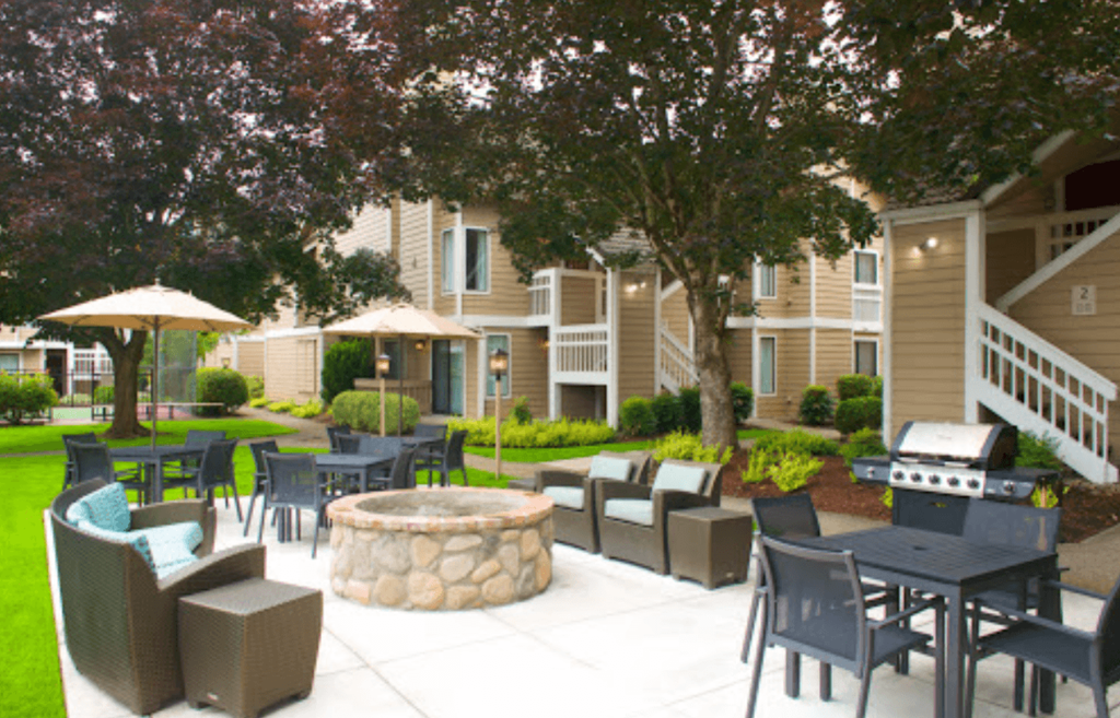 an outdoor lounge area with tables and chairs and a fire pit