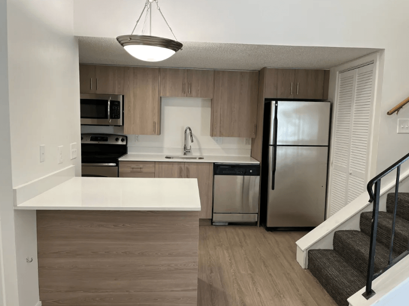 a kitchen with white countertops and a stainless steel refrigerator