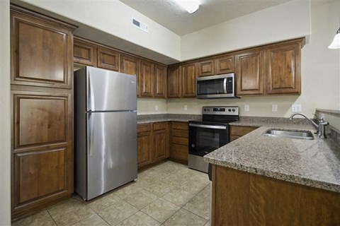 a kitchen with wooden cabinets and a stainless steel refrigerator