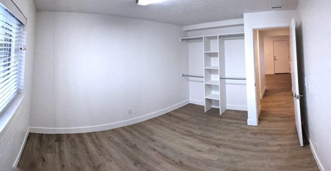 an empty room with white walls and wood floors and a closet
