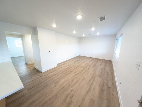 an empty living room with wood floors and white walls