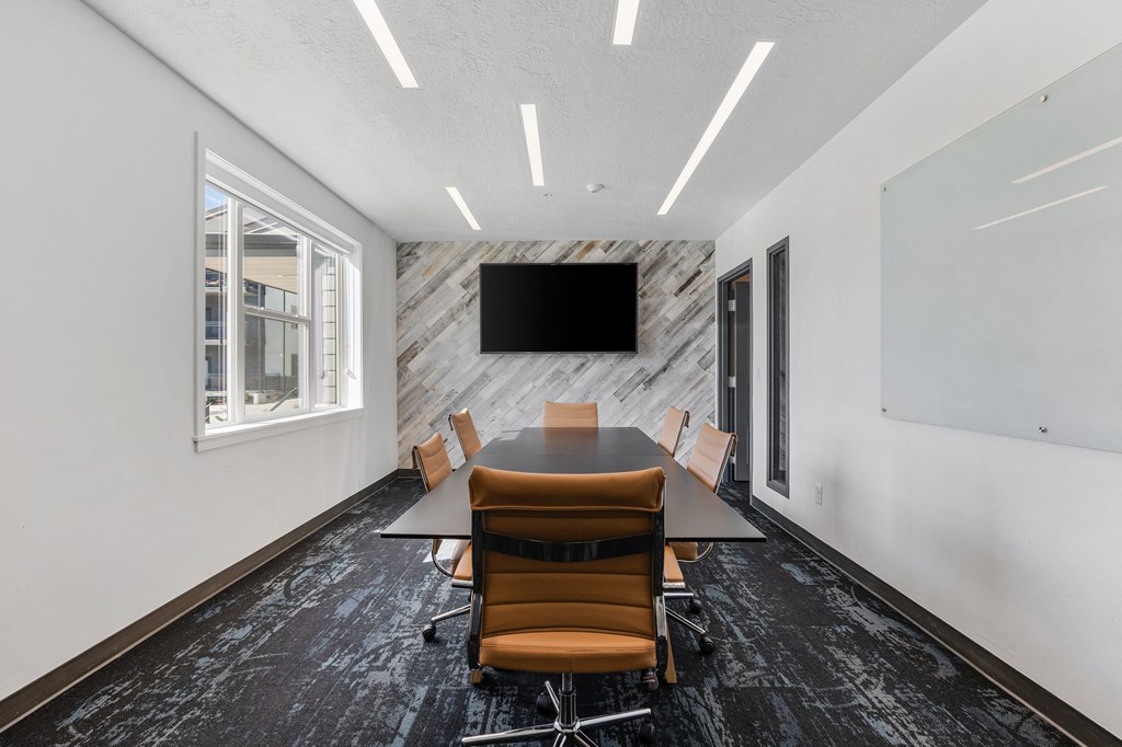 a conference room with a table and chairs and a tv on the wall at The Flats at Riverwoods, Provo, UT, 84604