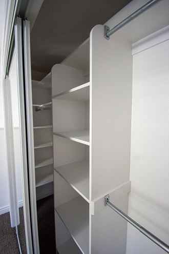 a closet with white shelves and a sliding glass door