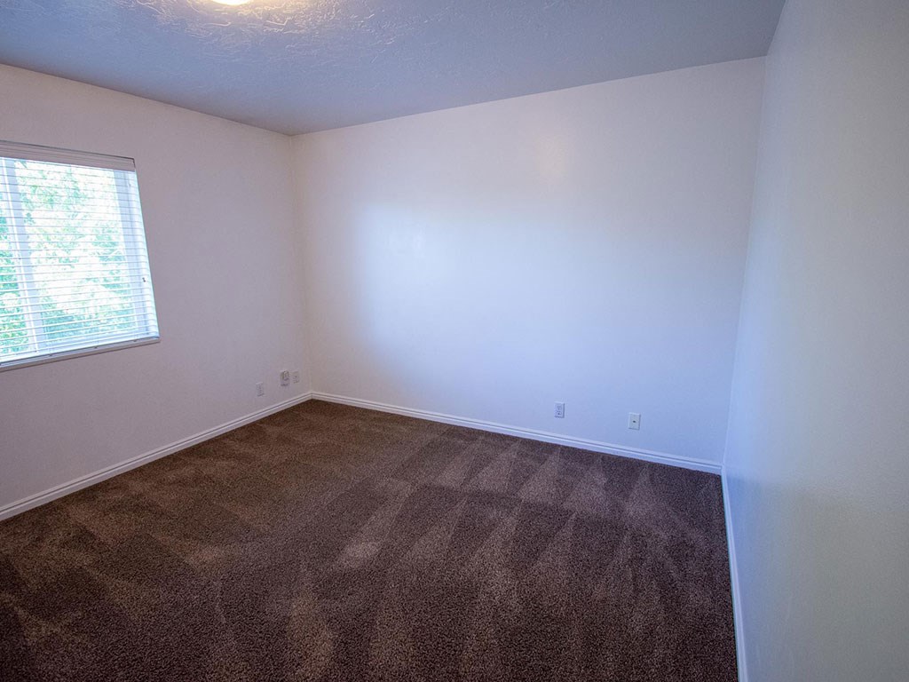 an empty room with a window and white walls