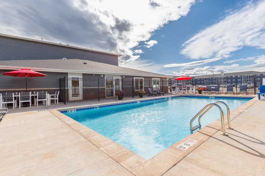 a swimming pool with chairs and umbrellas next to a building