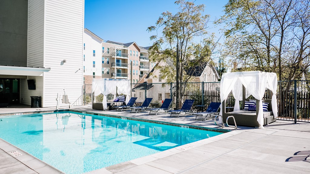 a swimming pool with blue lounge chairs and a building in the background