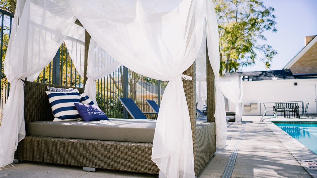 a bed with white canopy next to a pool